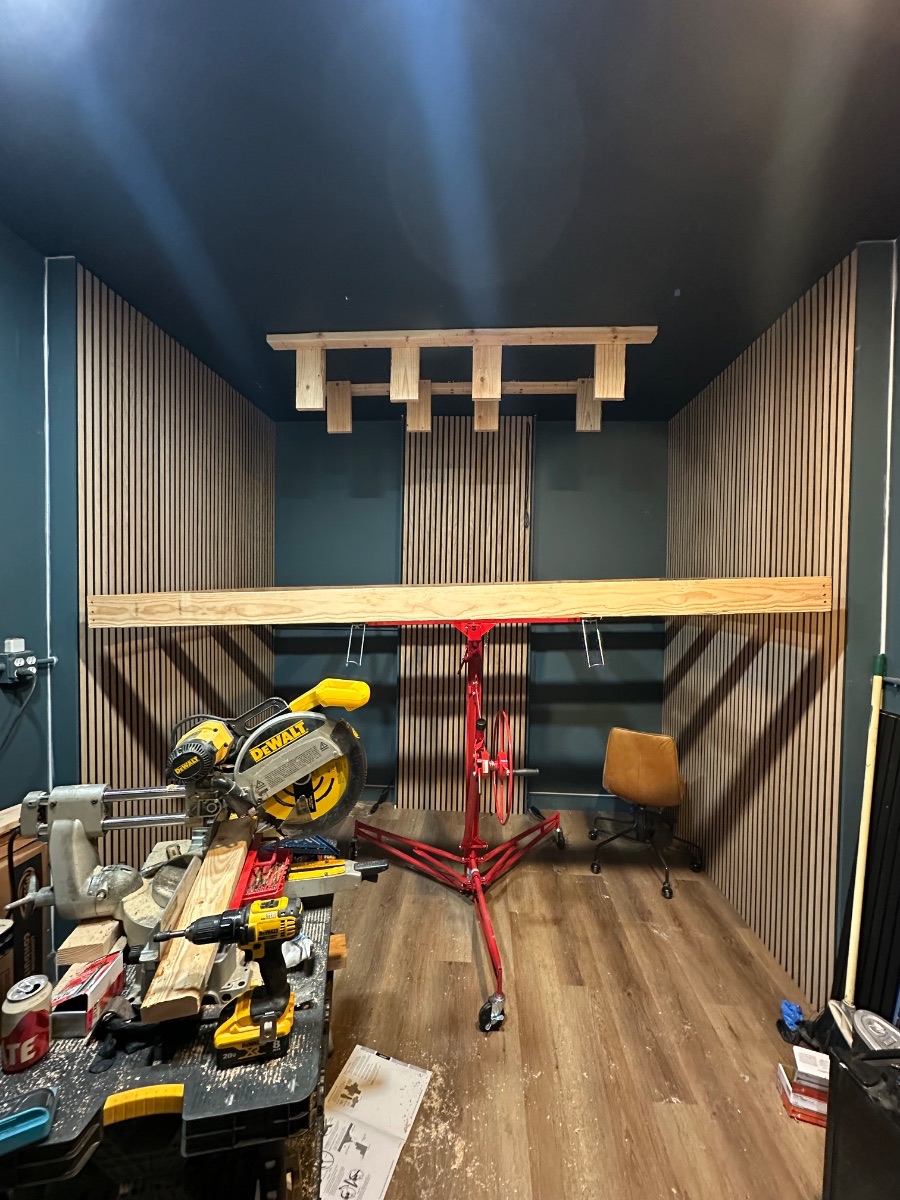 Panagraph Studios build — slat walls complete and the ceiling frame lifted on a panel hoist