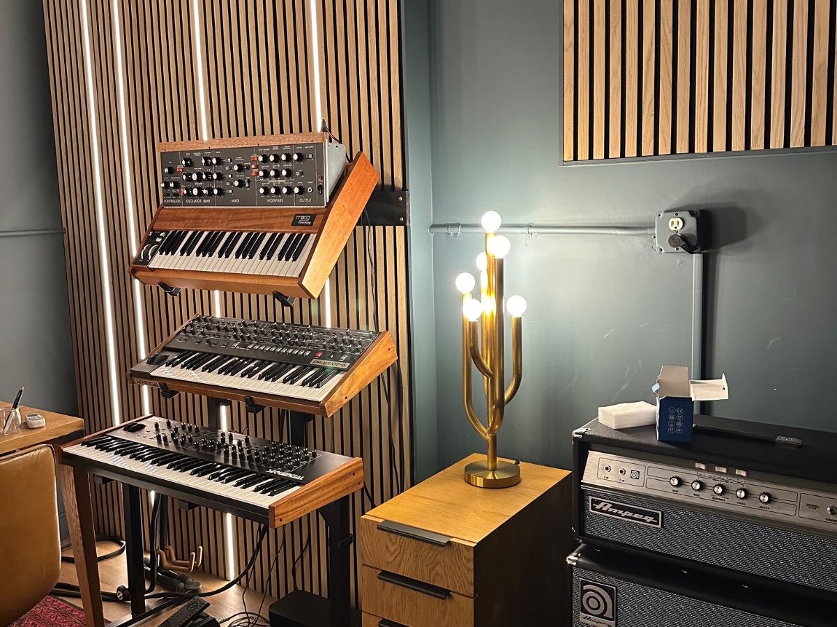 Panagraph Studios — vintage synthesizers racked against the slat wall, with integrated lighting and a brass lamp