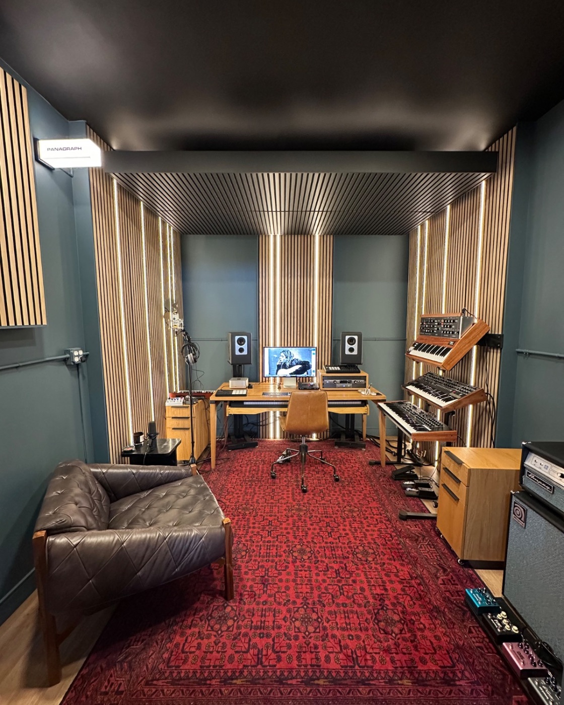 Panagraph Studios — the finished writing room: slat walls with integrated lighting, slatted ceiling, synthesizers, leather chair and a hand-woven rug