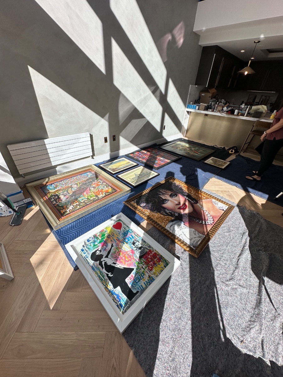Russian Hill gallery wall — framed works laid out on blankets on the floor before hanging