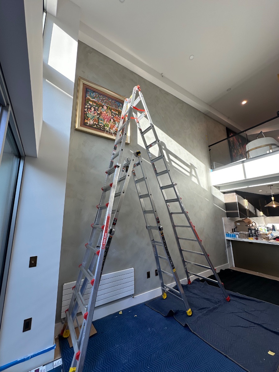 Russian Hill gallery wall — the first work hung high on the wall with ladders in place