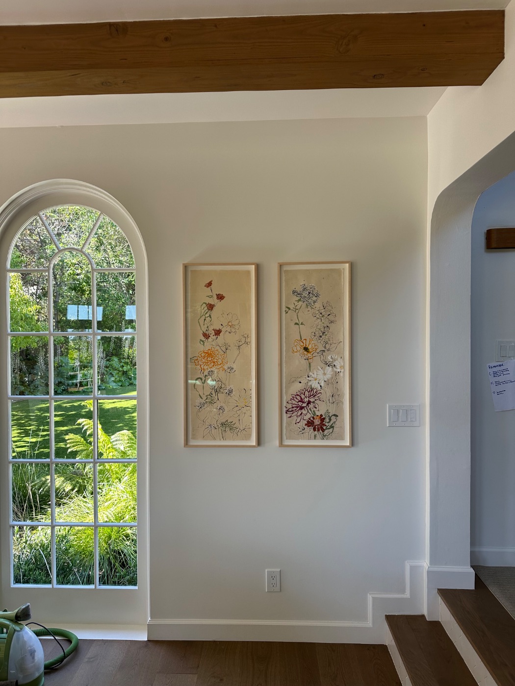 A pair of works hung beside an arched window