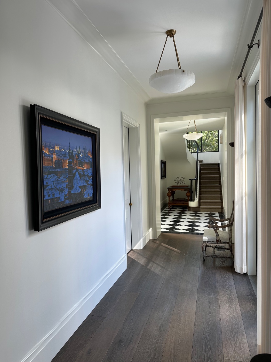 A framed painting in a hallway leading to a tiled entry