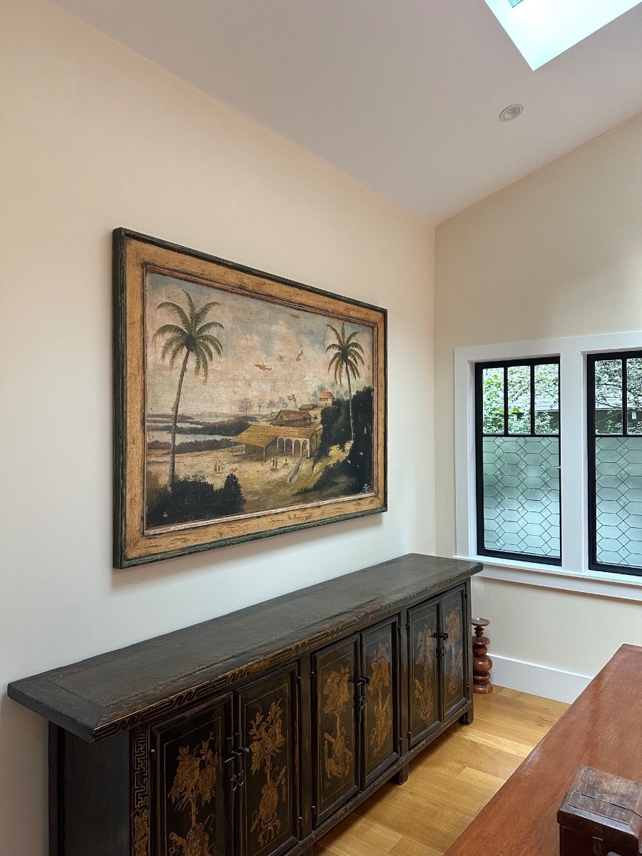 Fine art installation by Aero Luxe &mdash; An antique landscape above a chinoiserie sideboard beneath a skylight, Piedmont, California