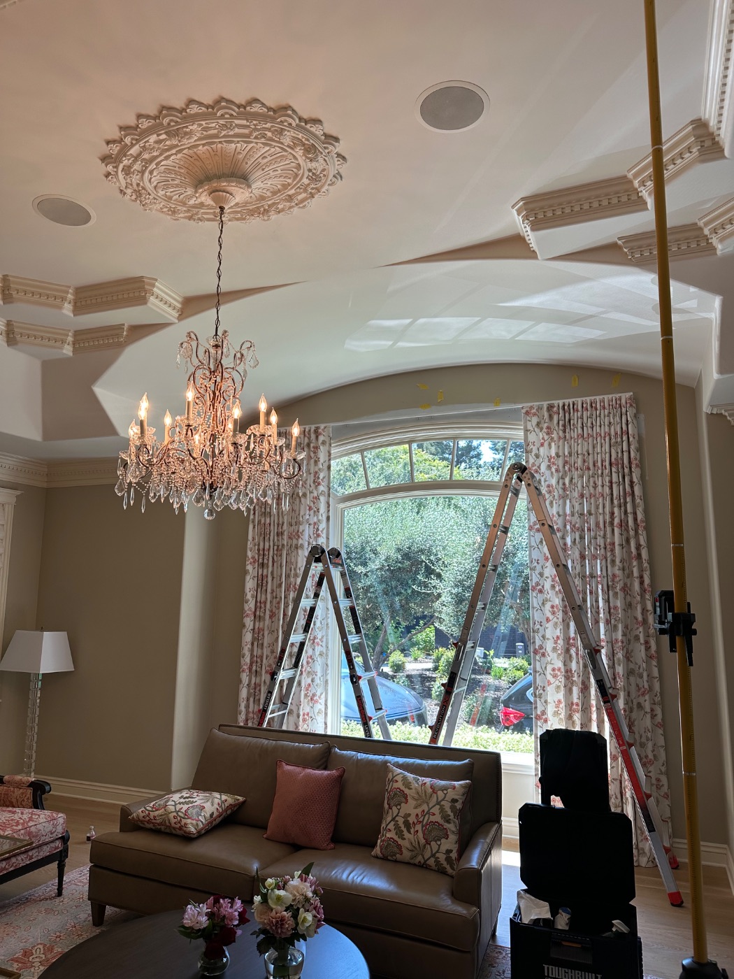 Floral pinch-pleat drapery hung across an arched bow window beneath a chandelier