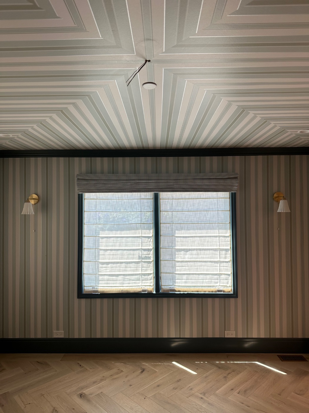 Roman shades installed in a papered room with painted trim