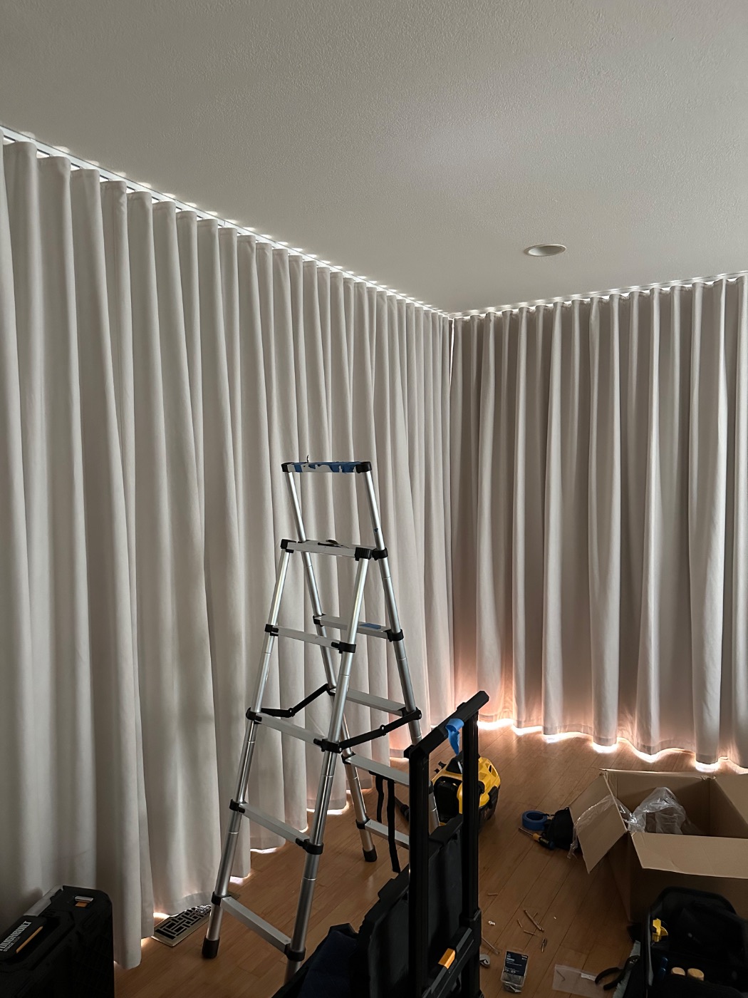 Ripplefold drapery on a concealed ceiling track wrapping a corner, backlit by daylight